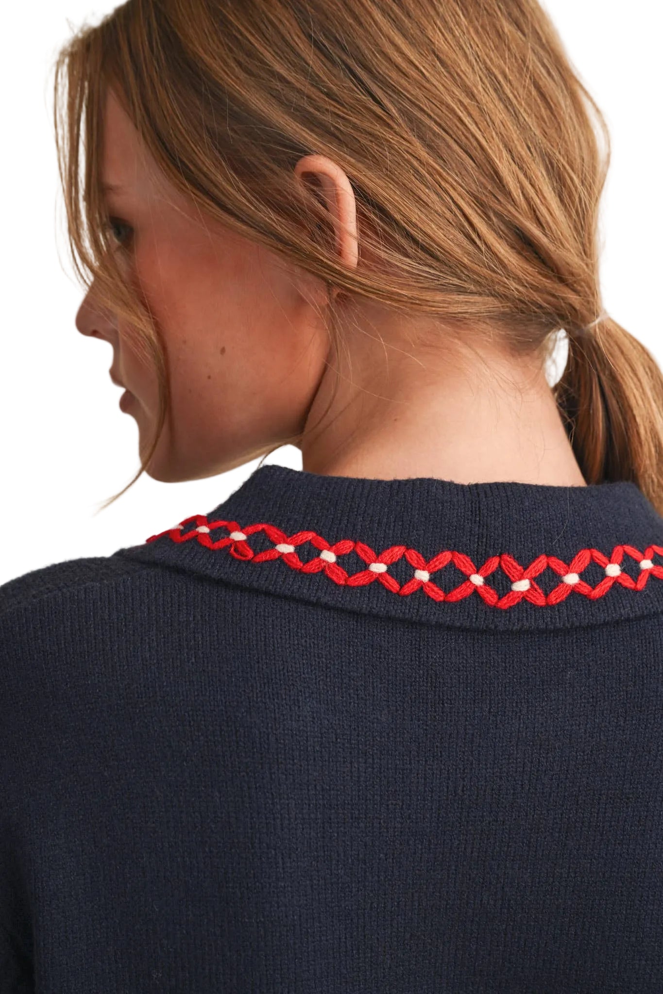 Close-up back view of a woman wearing a navy knit sweater with a red and white geometric patterned collar.