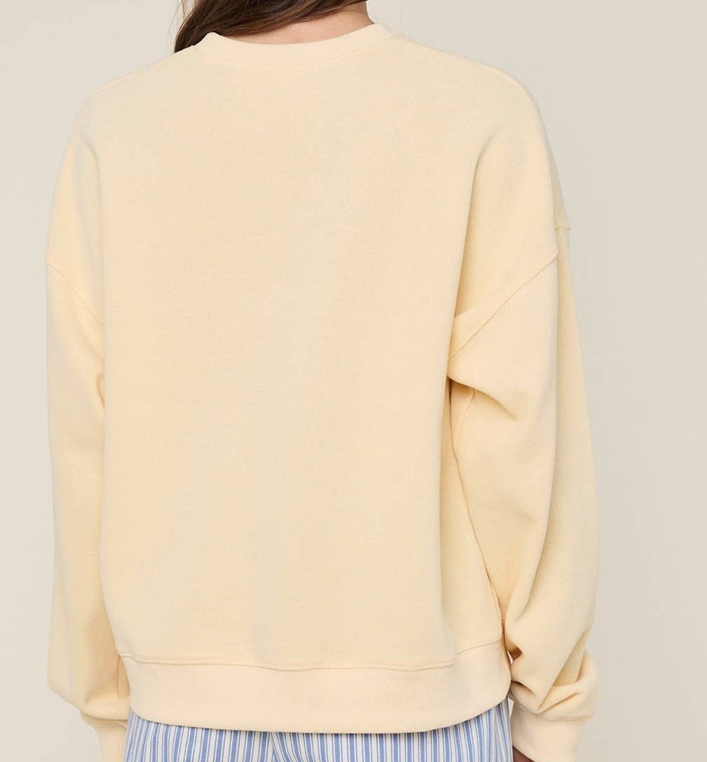 Person wearing a light yellow sweatshirt and blue patterned hat on a plain background