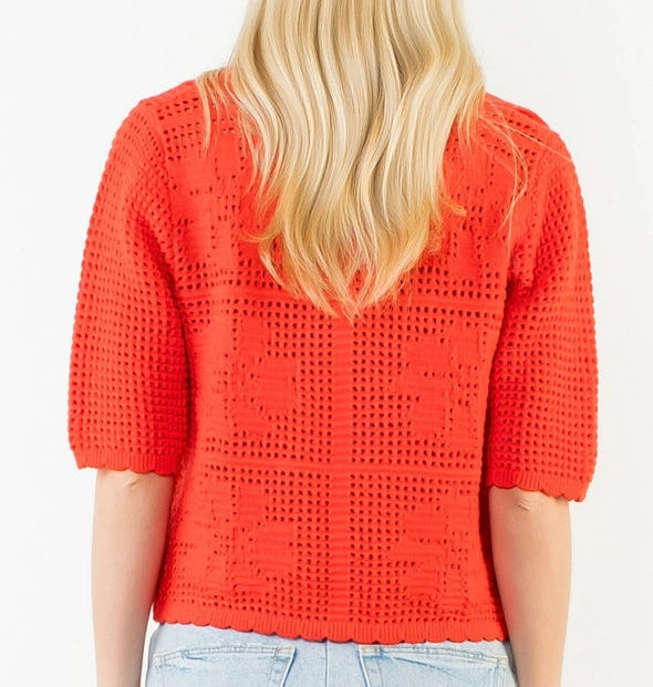 Person wearing a red crochet top and light blue denim skirt on a white background