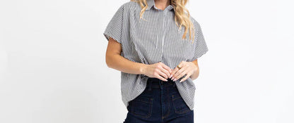 Woman wearing a gray striped shirt and dark blue jeans on a white background