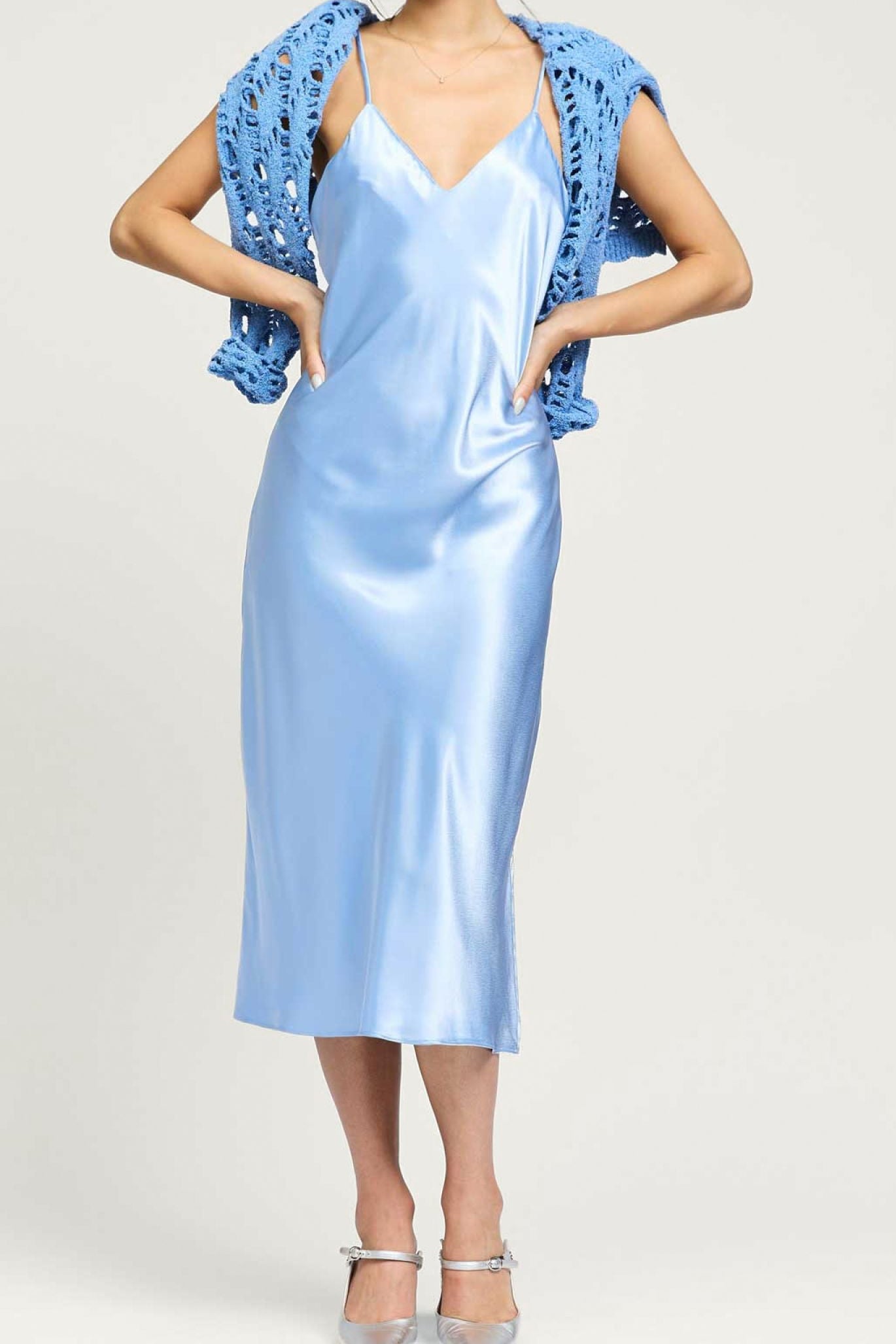 Woman wearing a light blue satin dress with a matching shawl on a white background