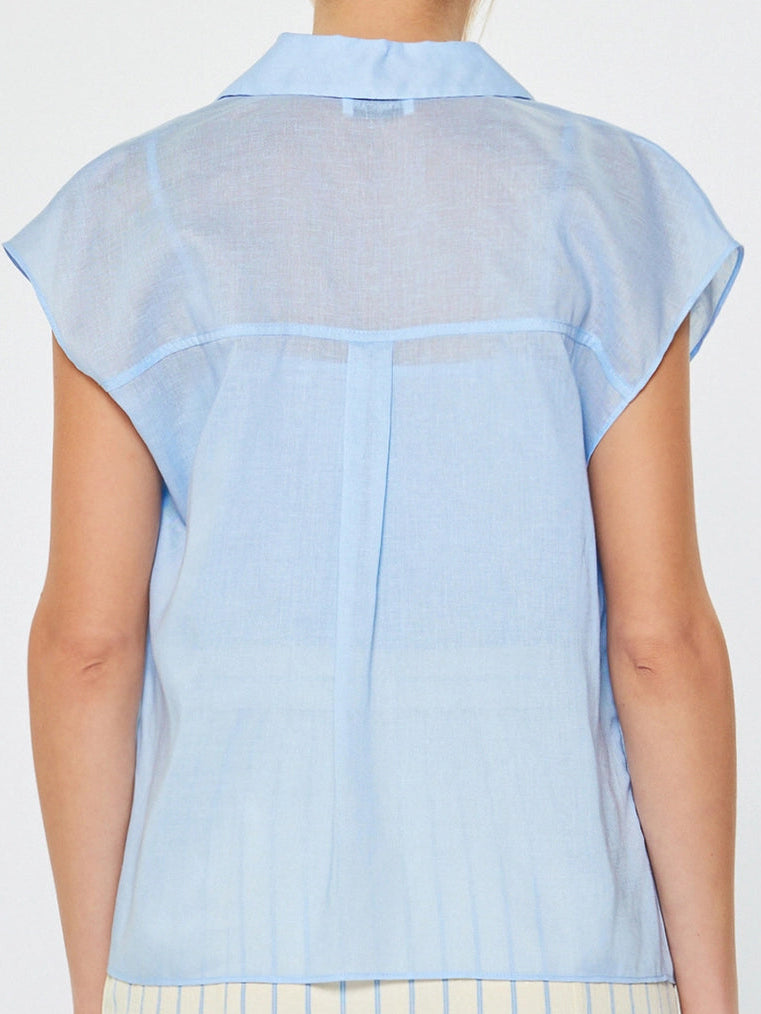 Woman wearing a light blue sheer blouse with a white background