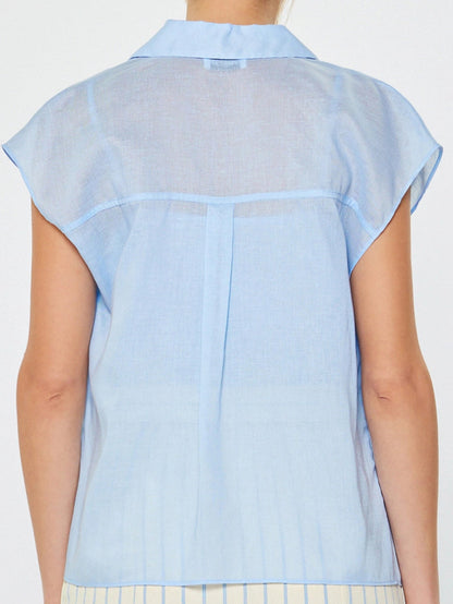 Woman wearing a light blue sheer blouse with a white background