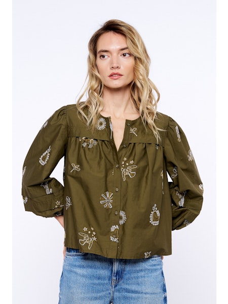 Woman wearing an olive green blouse with floral embroidery on a white background