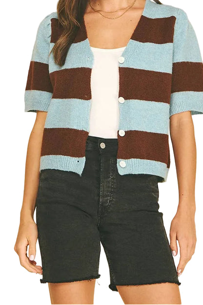 A woman modeling a short-sleeve knit cardigan with horizontal stripes in light blue and dark brown, worn over a white top and black denim shorts against a white background.