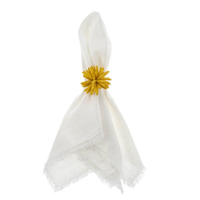White napkin with a yellow floral napkin ring on a white background