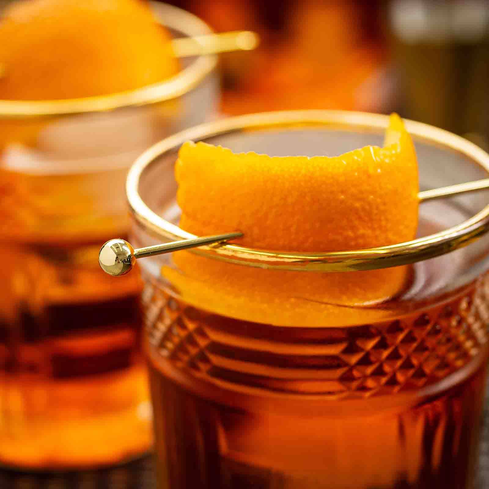 Close-up of a cocktail with an orange peel garnish in a glass.