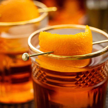 Close-up of a cocktail with an orange peel garnish in a glass.