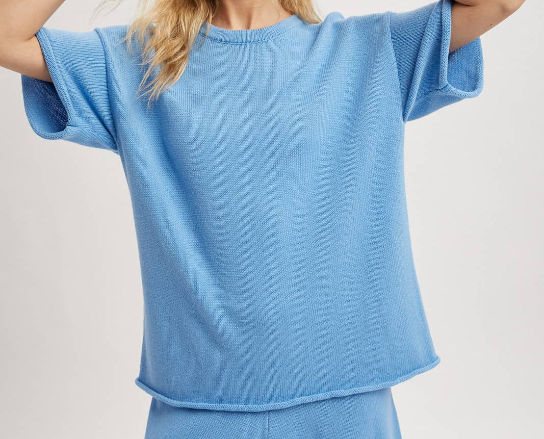 Woman wearing a light blue oversized top and shorts set on a plain background