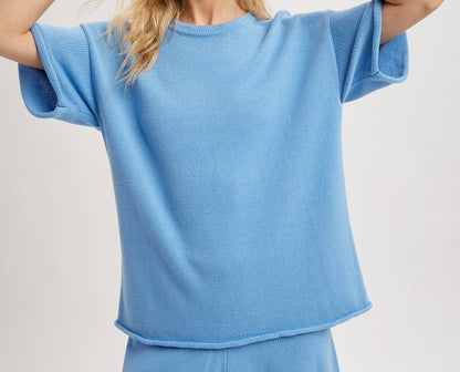 Woman wearing a light blue oversized top and shorts set on a plain background