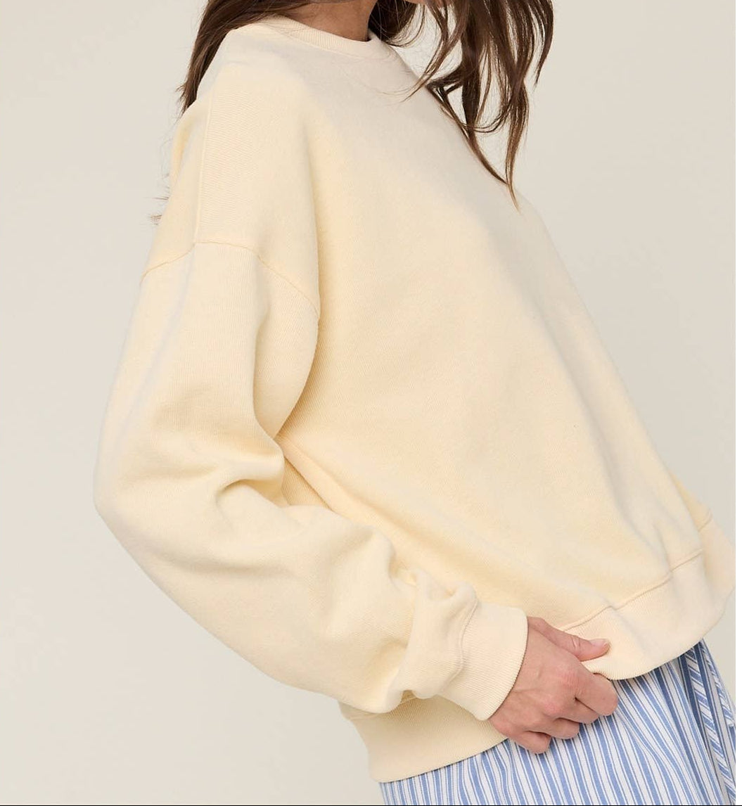 Person wearing a light yellow sweater and blue patterned hat against a neutral background