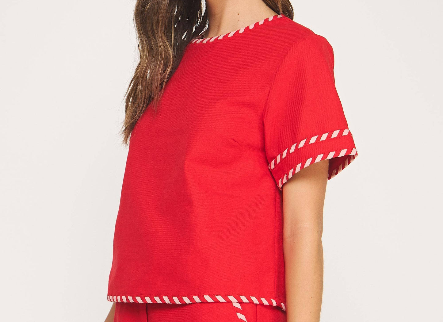 Woman wearing a red outfit with white trim on a white background