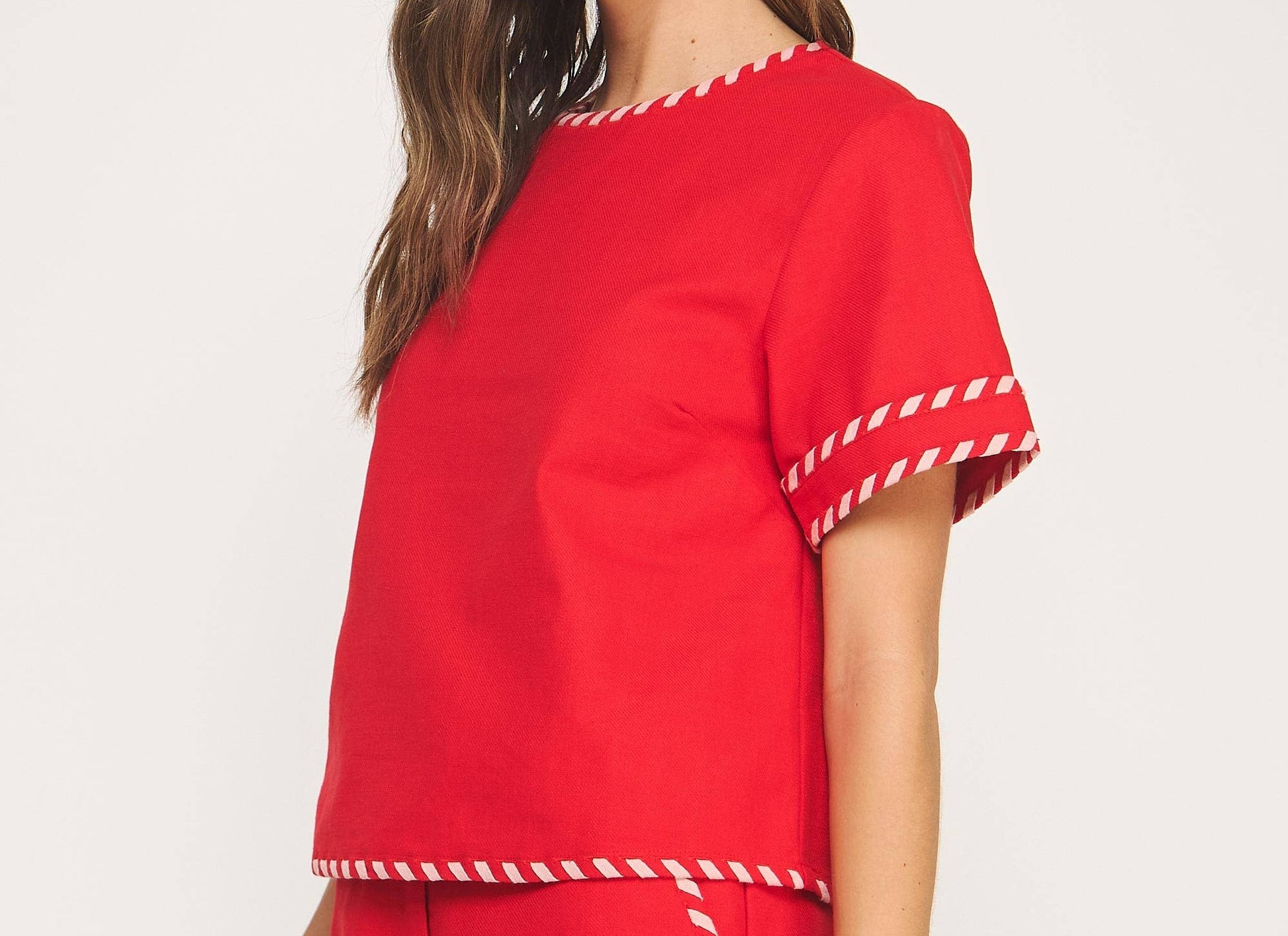 Woman wearing a red outfit with white trim on a white background