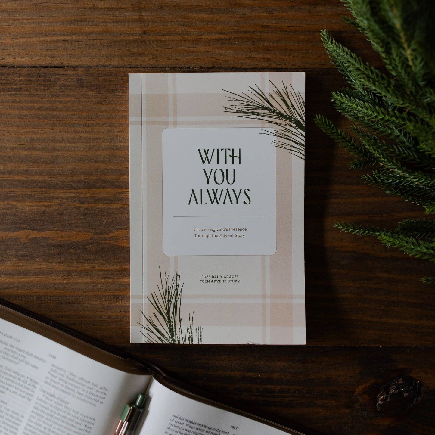 Book titled 'With You Always' on a wooden surface with greenery