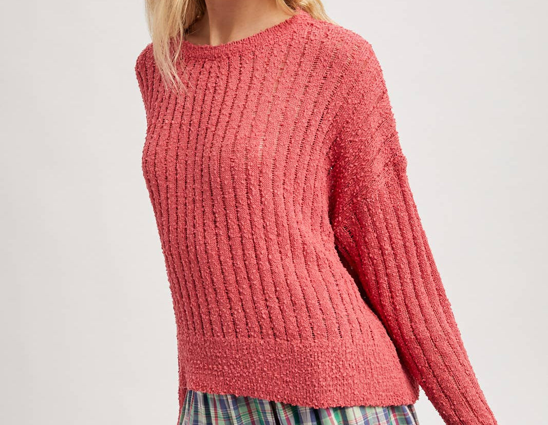 Woman wearing a pink knitted sweater and plaid skirt on a white background