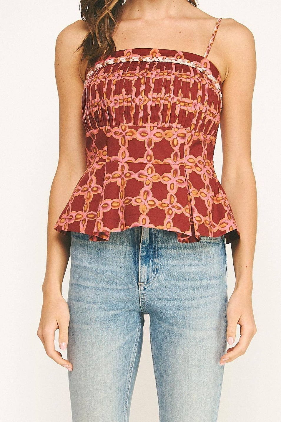 Woman wearing a floral peplum top and light blue jeans on a white background