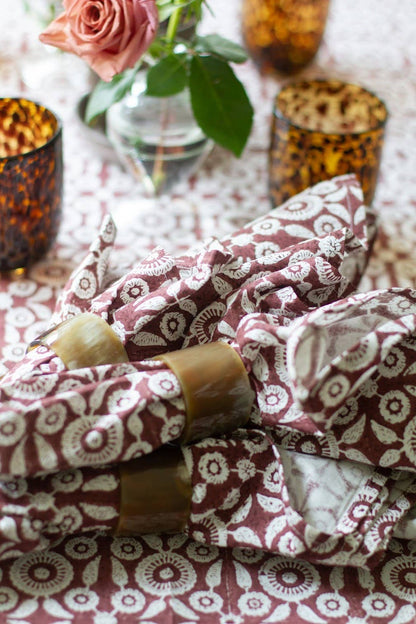 Patterned fabric wrapped around candles on a decorative table with flowers and candles.