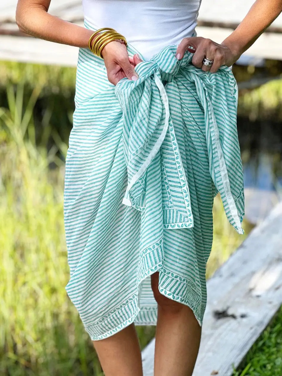 Person wearing a light green striped skirt with a blurred natural background
