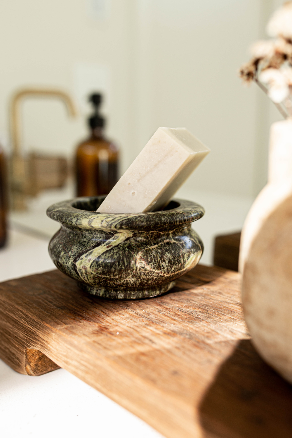 Bar of soap in a stone bowl on a wooden surface with a blurred background