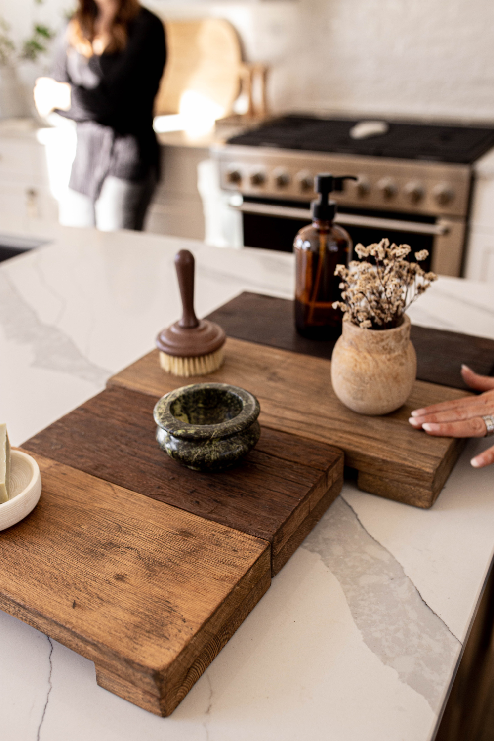 Wooden cutting board with kitchen items on a marble countertop