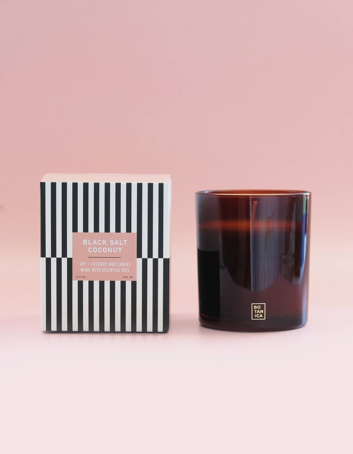 Candle and its packaging on a pink background