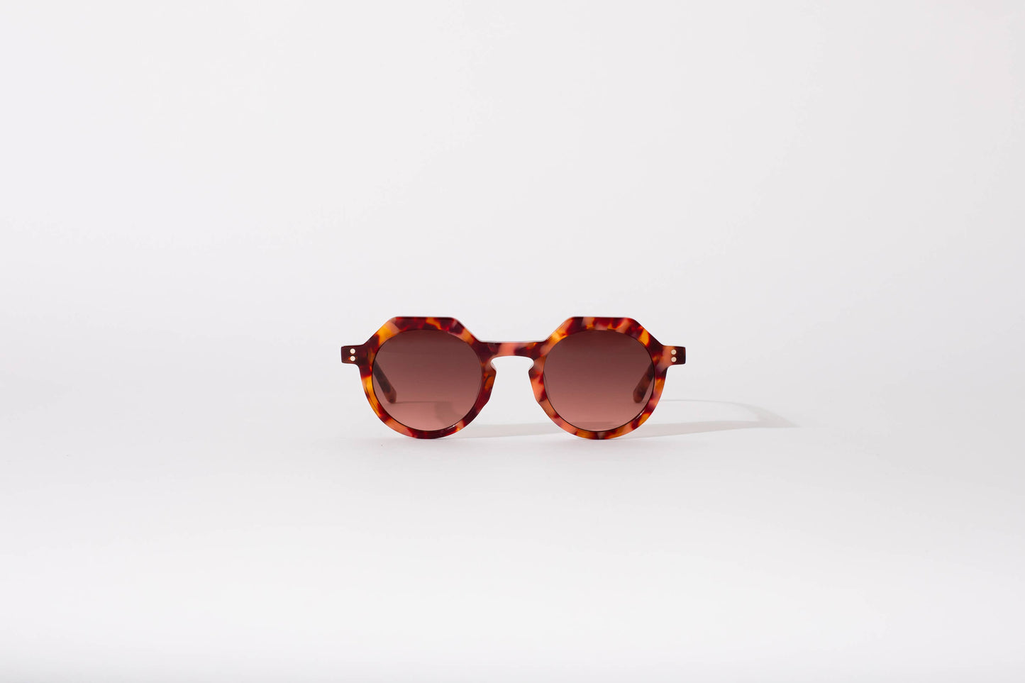 Sunglasses with tortoiseshell frame and brown lenses on a white background