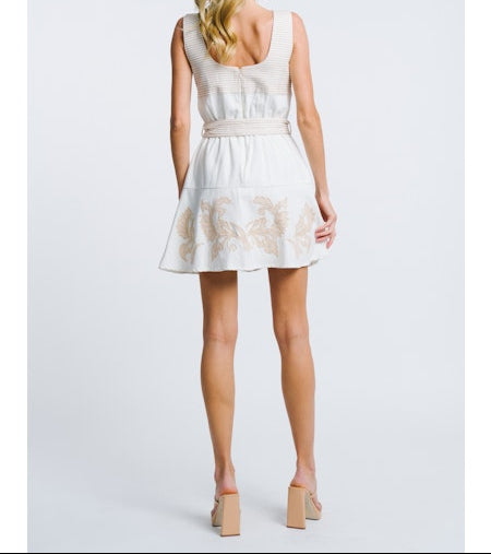 Woman wearing a white dress with floral lace details on a plain background