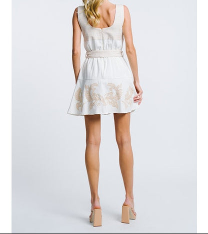 Woman wearing a white dress with floral lace details on a plain background