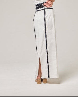 Woman wearing a white dress with black accents on a plain background