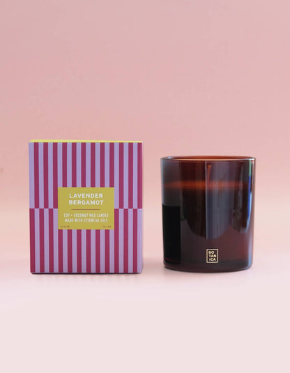 Candle with striped packaging on a pink background