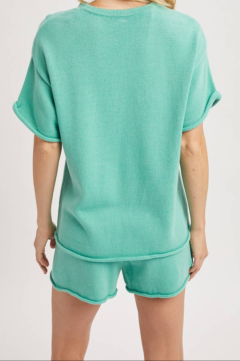 Woman wearing a teal pajama set on a plain background
