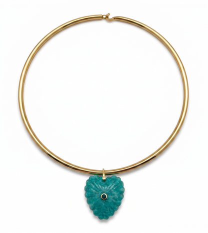A gold-plated circular collar necklace featuring a textured, carved turquoise pendant with a small black eye detail in the center, shown against a plain white background.