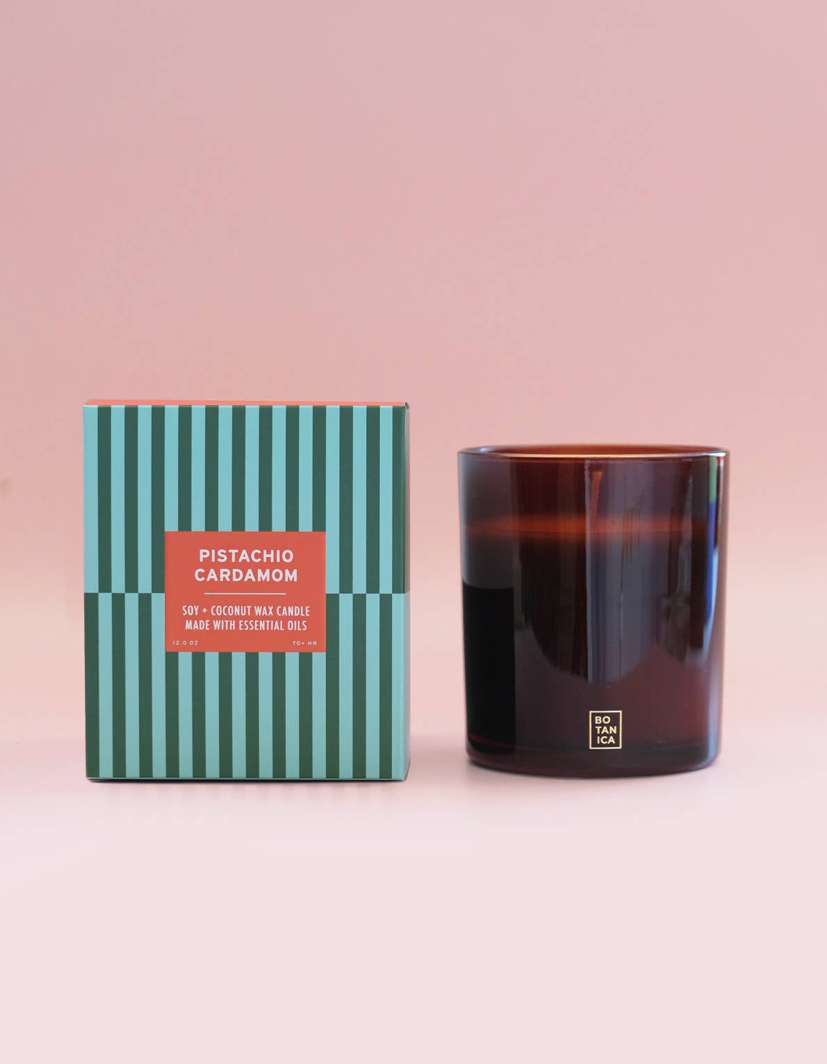 Candle with striped packaging on a pink background