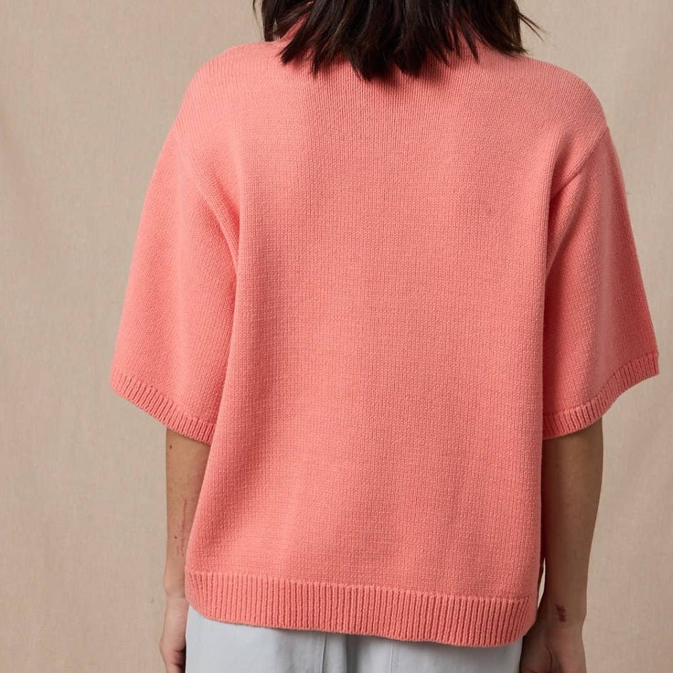 Person wearing a pink sweater against a beige background
