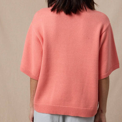 Person wearing a pink sweater against a beige background