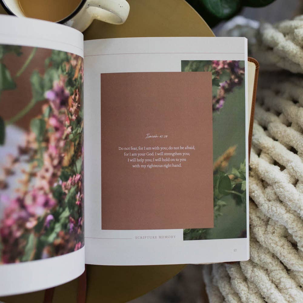 Open book with a brown page featuring text and floral images on a textured surface.