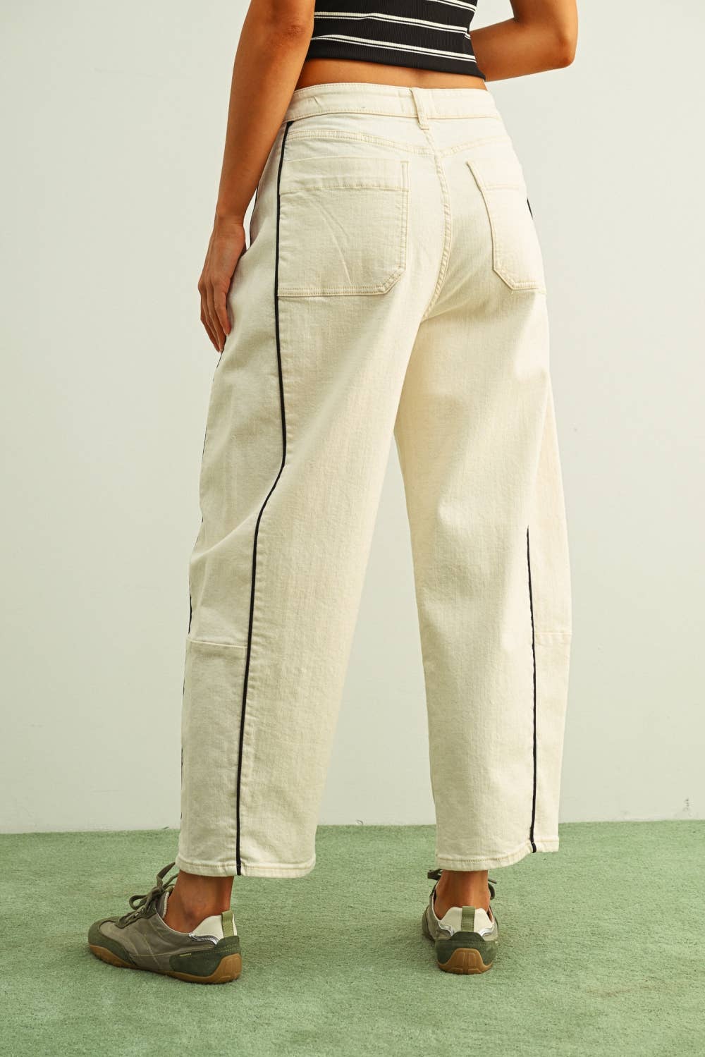 Person wearing white pants with black trim on a plain background