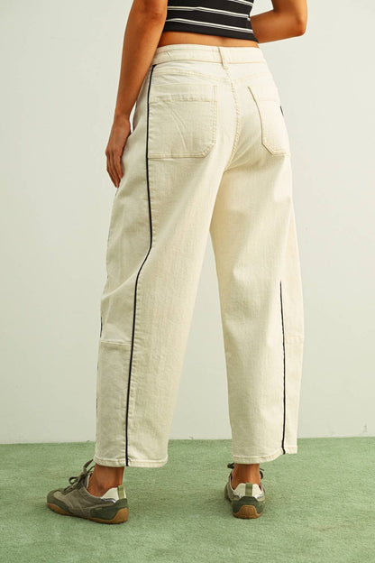 Person wearing white pants with black trim on a plain background