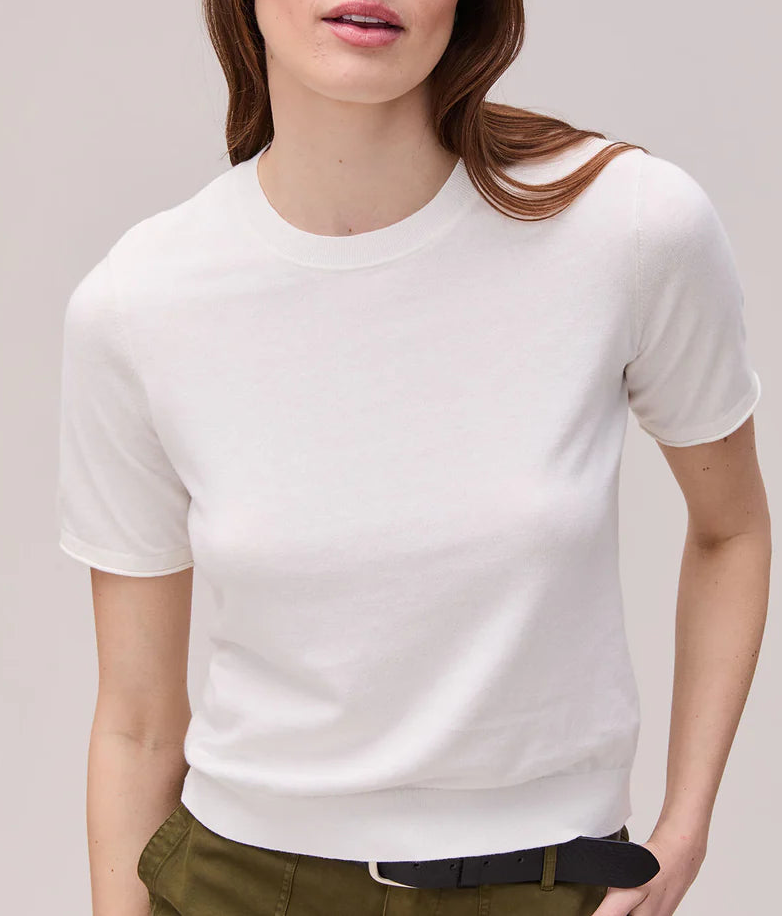 Woman wearing a white t-shirt and green pants against a plain background