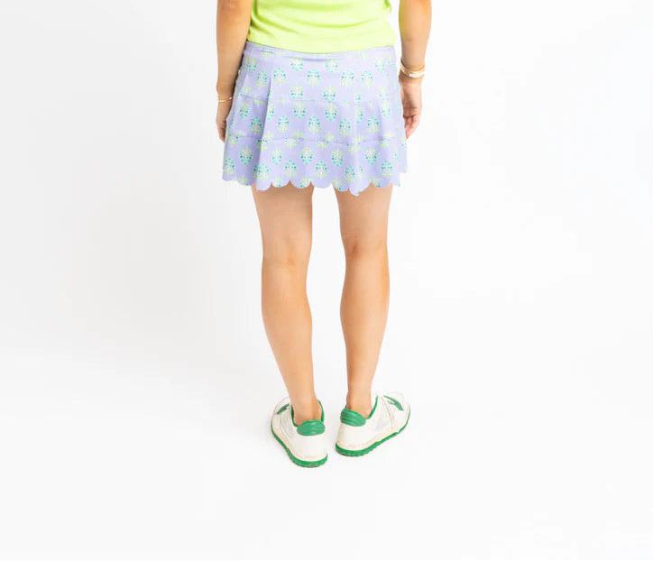 Woman wearing a light green tank top and a polka dot skirt on a white background