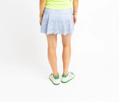 Woman wearing a light green tank top and a polka dot skirt on a white background