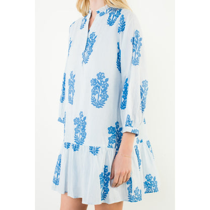 White dress with blue floral pattern worn by a model on a white background