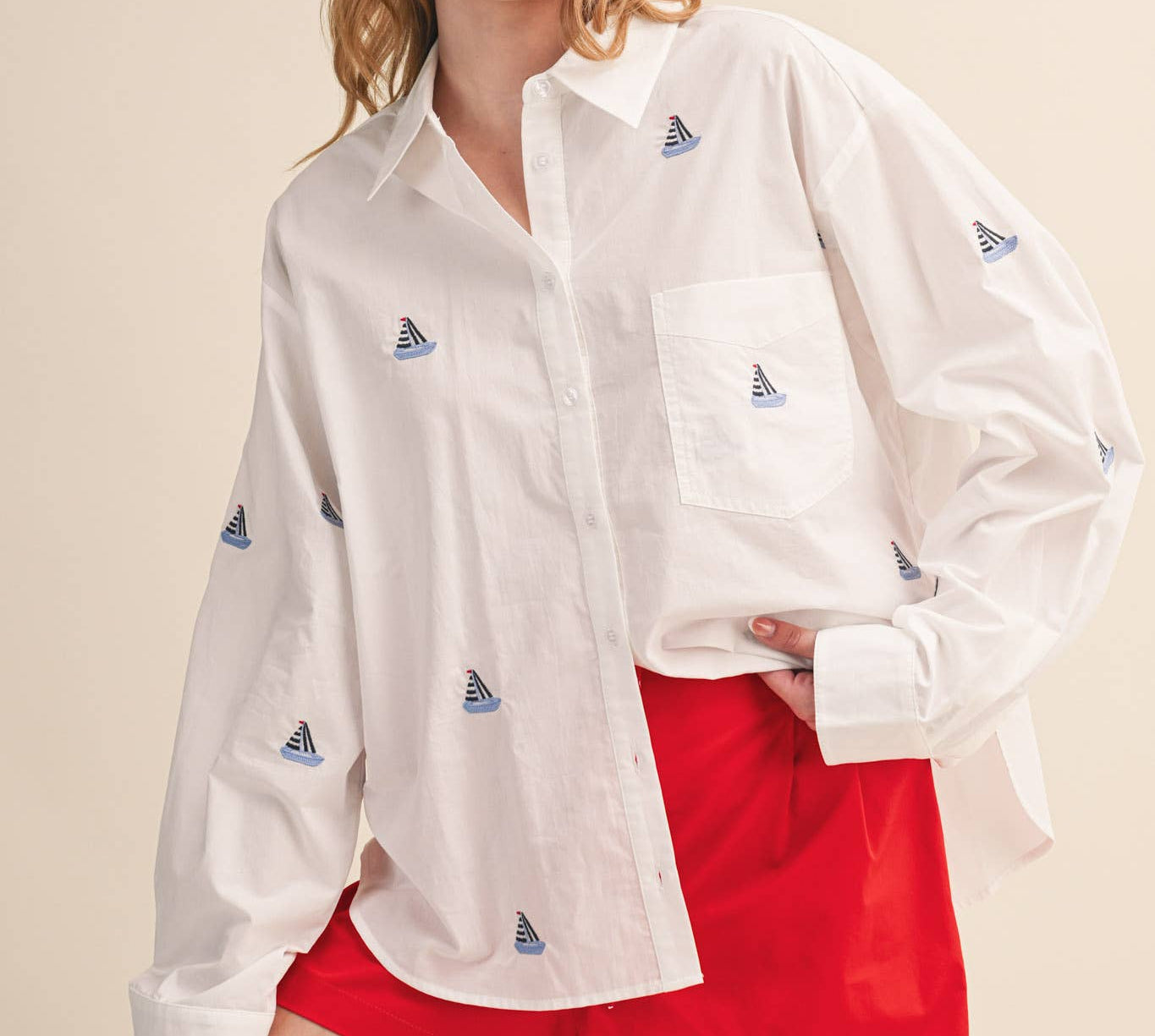 Woman wearing a white shirt with small logos and white pants on a beige background