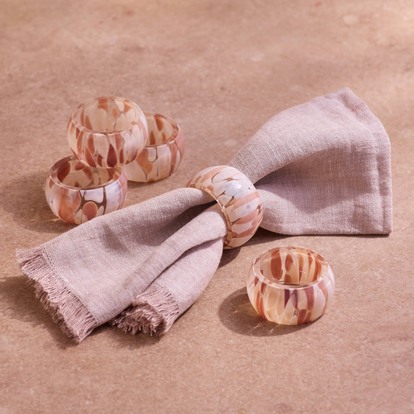 Marbled patterned bangles on a beige fabric with a beige background