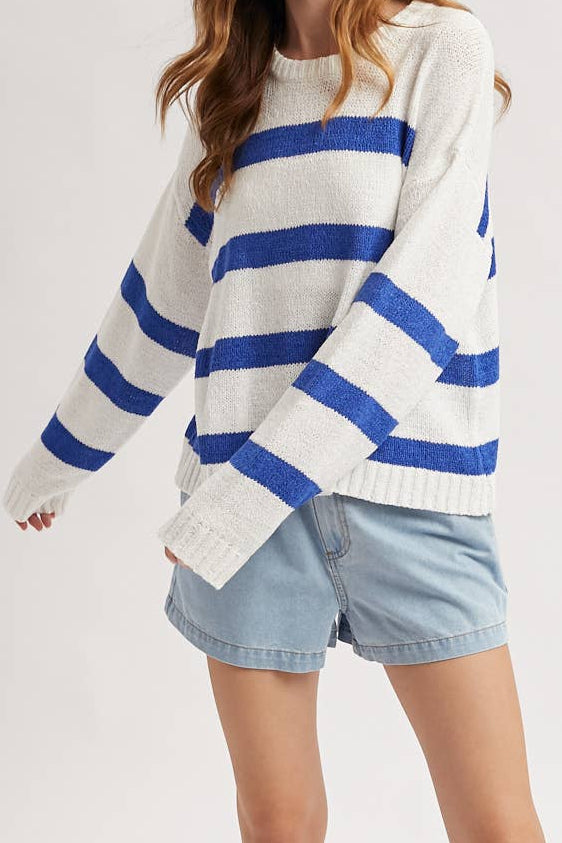 Woman wearing a white sweater with blue stripes and denim shorts on a white background