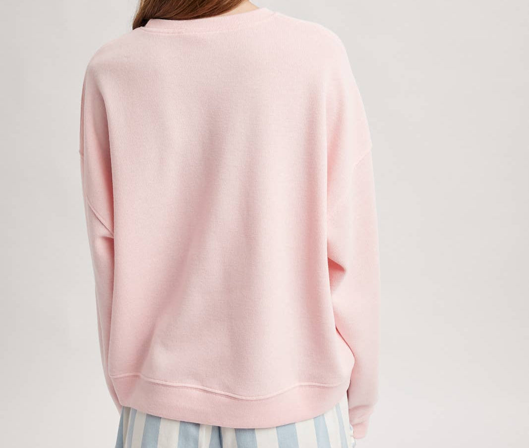 Person wearing a pink sweatshirt and striped shorts on a light gray background