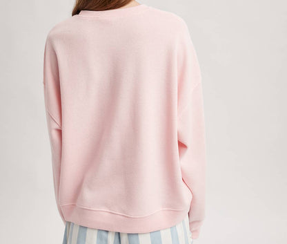 Person wearing a pink sweatshirt and striped shorts on a light gray background