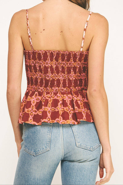 Woman wearing a patterned tank top and jeans on a white background