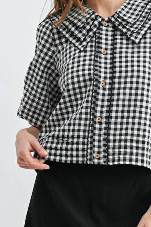 Woman wearing a black and white checkered shirt and black skirt on a white background