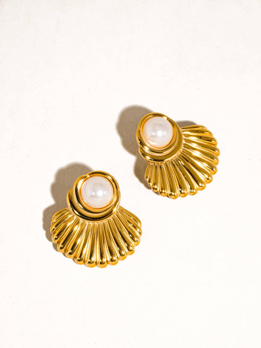Gold earrings with pearl-like centers on a white background